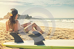 Surfer girl lying on the beach and watching to the ocean