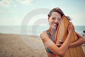 Surfer girl posing with her surfboard on the beach