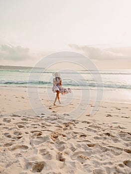 Surfer girl with surfboard on a beach at sunset