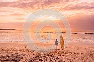 Surfer girl with surfboard at beach. Surfer woman with sunset or sunrise colors