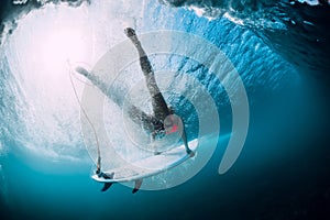 Surfer girl with surfboard dive with under ocean wave. Underwater view