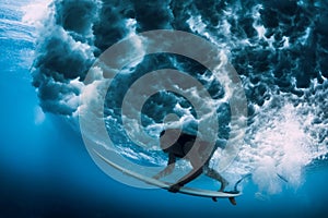 Surfer girl with surfboard dive underwater with under big ocean wave