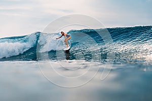 Surfer girl at surfboard on wave in tropical ocean. Sporty woman during surfing