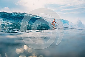 Surfer girl at surfboard on wave in tropical ocean. Sporty woman during surfing