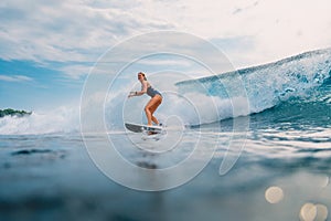 Surfer girl at surfboard on wave in tropical ocean. Sporty woman during surfing