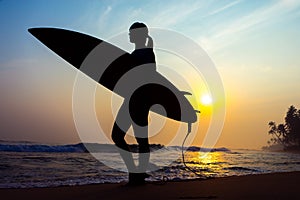 Surfer girl surfing looking at ocean beach sunset. Silhouette w