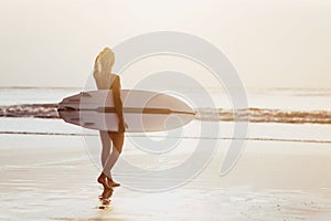 Surfer girl surfing looking at ocean beach sunset