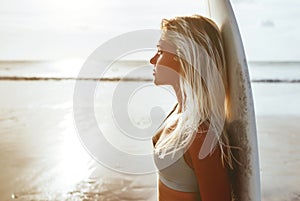 Surfer girl surfing looking at ocean beach sunset