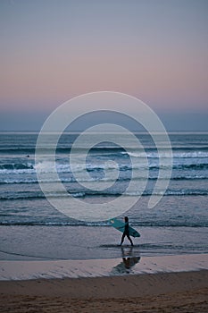 Surfer girl walkin on the beach after sunset photo