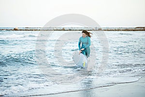 Surfer girl walking with board on the sandy beach. Surfer female.Beautiful young woman at the beach. water sports. Healthy Active