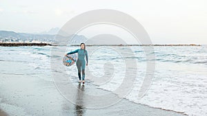 Surfer girl walking with board on the sandy beach. Surfer female.Beautiful young woman at the beach. water sports. Healthy Active