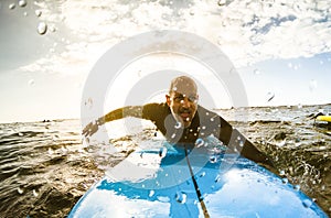 Surfer guy paddling with surfboard at sunset in Tenerife