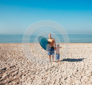 Surfer and his son are going to surf in the ocean in a sunny day