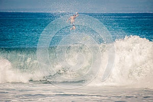 Surfer jumps on board on wave