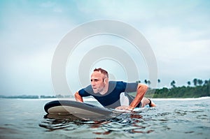 Surfer man floats on surf board, waits a waves