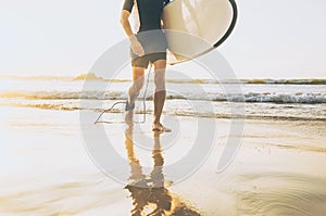Surfer man with long board walking out fro sea waves on sunny ocean beach. Active vacation spending time concept image