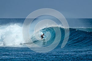 Surfer on perfect blue big tube wave, empty line up, perfect for surfing, clean water in Indian Ocean