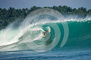 Surfer on perfect blue big tube wave, empty line up, perfect for surfing, clean water, Indian Ocean in Mentawai islands