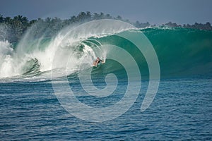 Surfer on perfect blue big tube wave, empty line up, perfect for surfing, clean water, Indian Ocean in Mentawai islands