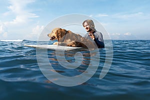 Surfer Portrait. Surfing Man With Dog On Surfboard Swimming In Ocean. Water Sport As Hobby.