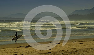 Surfer on Public beach with waves and mountains Tofino British Columbia