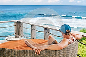 Surfer relaxing in lounge on roof veranda with sea view