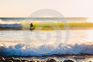 Surfer ride on perfect ocean wave at sunset. Winter surfing in swimsuit