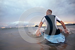 Surfer sits on surfboard on the waves in sunset time