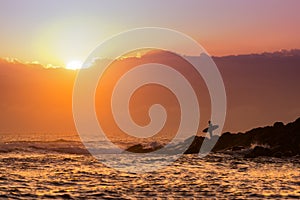 Silhouette of a surfer at sunrise or sunset