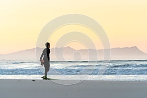 A surfer stretching at Betty`s Bay beach at sunset in the Western Cape, South Africa