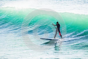Surfer on sup board on ocean waves. Stand up paddle boarding in sea