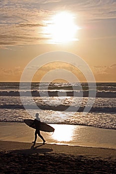 Surfer with surf board on beach, Fistral Bay, UK