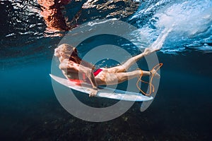 Surfer with surf board dive underwater with under big ocean wave