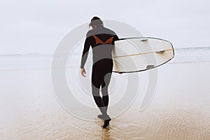 Surfer with surfboard goes to the ocean