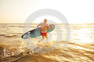 Surfer with surfboard looking at sunset at Goa India