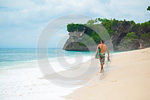 Surfer. Surfing Man With Surfboard Walking On Sandy tropical Beach. Healthy Lifestyle, water activities, Water Sport. Beautiful