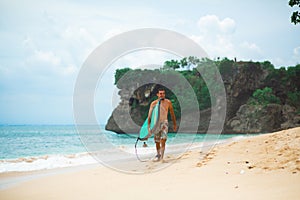 Surfer. Surfing Man With Surfboard Walking On Sandy tropical Beach. Healthy Lifestyle, water activities, Water Sport. Beautiful