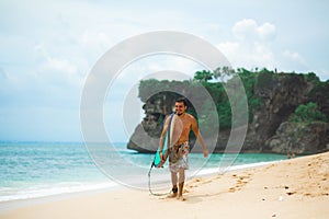 Surfer. Surfing Man With Surfboard Walking On Sandy tropical Beach. Healthy Lifestyle, water activities, Water Sport. Beautiful