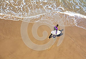 Surfer walking along the sea was shot from top