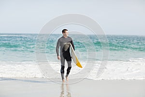 Surfer walking on the beach with a surfboard