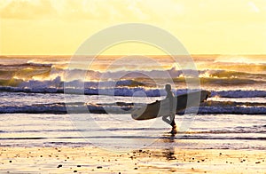 Surfer walking sunset