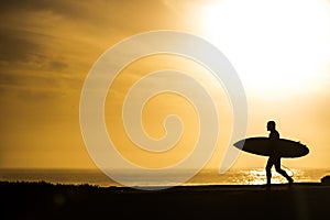 Surfer walking in the sunset in Santa Cruz, California