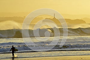 Surfer walking towards the sea at sunrise in Santander photo