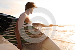 Surfer walking by water looking at waves