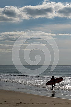 Surfer walks into the Atlantic ocean on the French Cote d`Argent to catch some waves