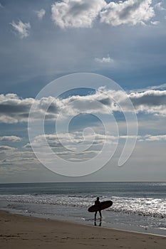Surfer walks into the Atlantic ocean on the French Cote d`Argent to catch some waves