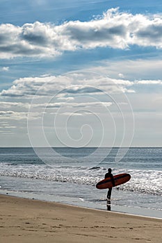 Surfer walks into the Atlantic ocean on the French Cote d`Argent to catch some waves