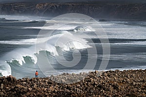 A surfer watching a set of waves breaking at the Bordeira Beach Praia da Bordeira in Algarve photo