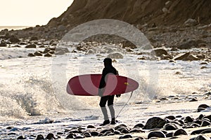 Surfer watching waves crashing on a rocky shore