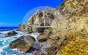 Surfer waves turquoise blue water rocks cliffs boulders Puerto Escondido